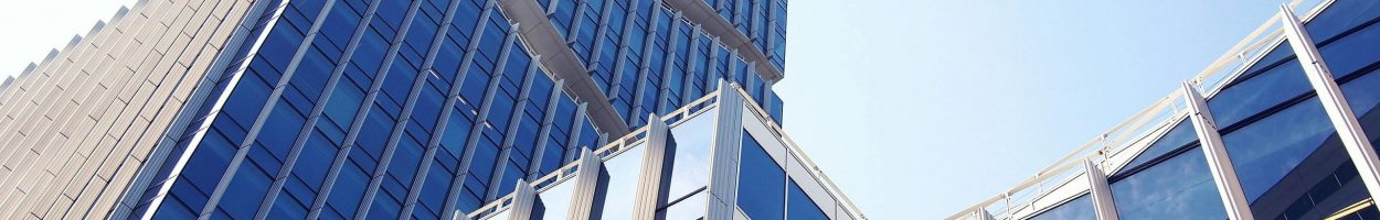 Low-angle shot of a modern skyscraper with reflective glass design under a clear blue sky.